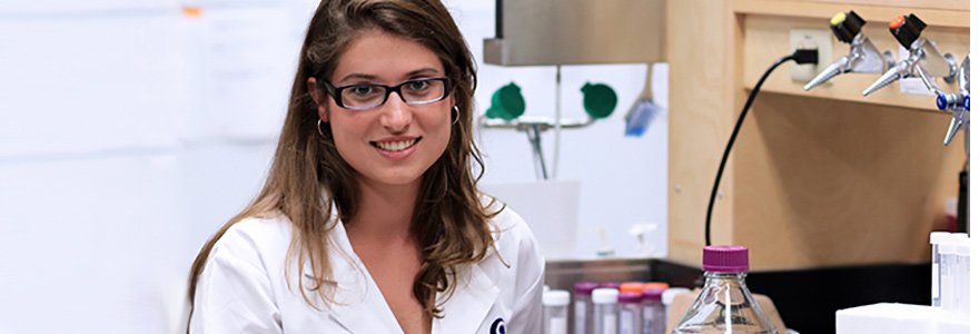 A graduate student in a lab looking at the camera, smiling